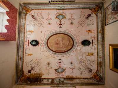 ...da un soffitto con volta a crociera decorato con greche, statuette dipinte, bucrani e volti